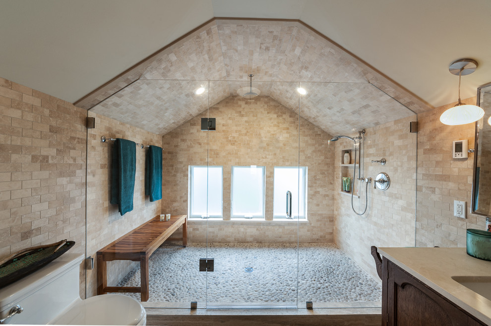 Cette image montre une salle de bain principale traditionnelle en bois foncé avec un lavabo encastré, une douche ouverte, WC à poser, un carrelage beige, un carrelage de pierre, un mur beige, un sol en galet, une cabine de douche à porte battante et un placard avec porte à panneau encastré.