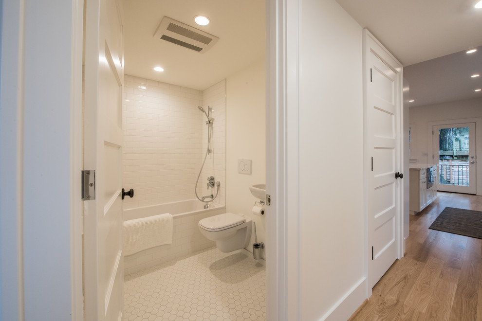 Cette image montre une petite salle d'eau minimaliste avec une baignoire en alcôve, un combiné douche/baignoire, WC suspendus, un carrelage blanc, un carrelage métro, un mur blanc, un sol en carrelage de céramique et un sol blanc.