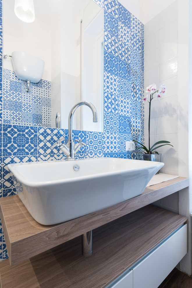 Immagine di una piccola stanza da bagno contemporanea con lavabo a consolle, nessun'anta, ante in legno scuro, WC a due pezzi, piastrelle blu e piastrelle in ceramica