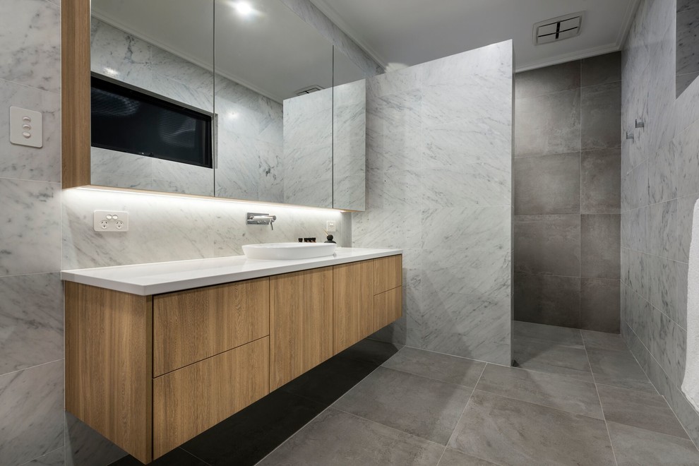 Foto på ett stort funkis badrum, med skåp i ljust trä, ett hörnbadkar, en öppen dusch, grå kakel, grå väggar och med dusch som är öppen