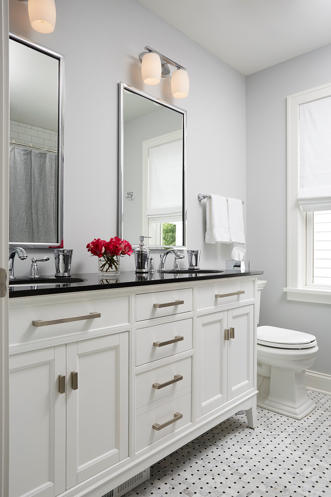 Inspiration för mellanstora klassiska en-suite badrum, med ett undermonterad handfat, vita skåp, en dusch/badkar-kombination, svart och vit kakel, grå väggar, mosaikgolv, luckor med infälld panel, en toalettstol med separat cisternkåpa, porslinskakel och bänkskiva i akrylsten