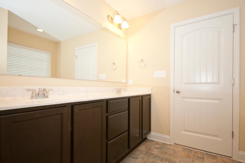 Modelo de cuarto de baño actual con lavabo integrado, puertas de armario de madera en tonos medios, ducha empotrada y sanitario de dos piezas