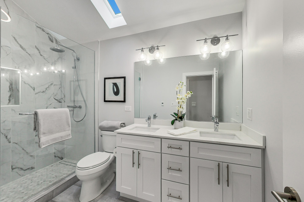 Inspiration for a traditional bathroom in Chicago with shaker cabinets, white cabinets, an alcove shower, white tiles, white walls, a submerged sink, grey floors, white worktops, double sinks and a built in vanity unit.