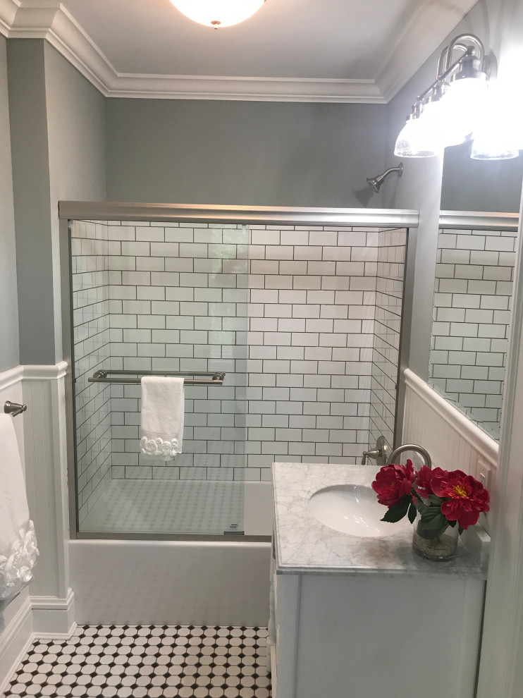 На фото: детская ванная комната в классическом стиле с фасадами в стиле шейкер, белыми фасадами, ванной в нише, душем в нише, раздельным унитазом, белой плиткой, плиткой кабанчик, серыми стенами, полом из керамической плитки, врезной раковиной, мраморной столешницей, белым полом, душем с раздвижными дверями, разноцветной столешницей, тумбой под одну раковину, напольной тумбой и панелями на стенах