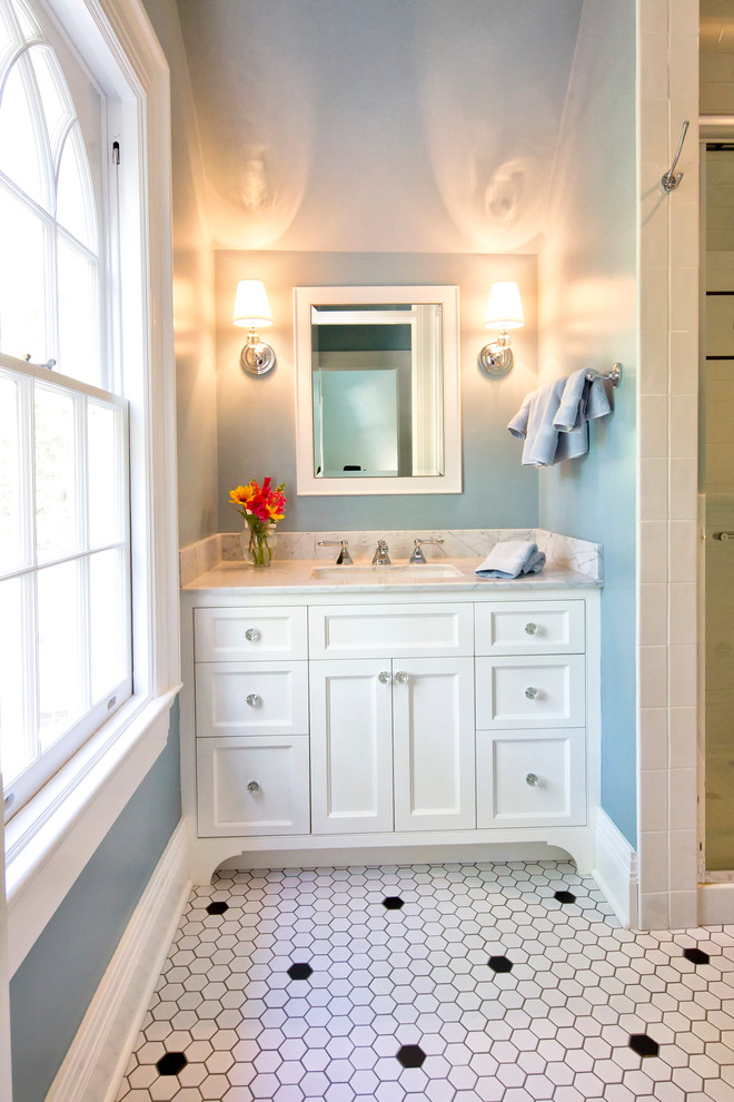 Inredning av ett klassiskt grå grått badrum, med mosaik, luckor med infälld panel, vita skåp, en dusch i en alkov, vit kakel, blå väggar, klinkergolv i porslin, ett undermonterad handfat, marmorbänkskiva, vitt golv och dusch med gångjärnsdörr