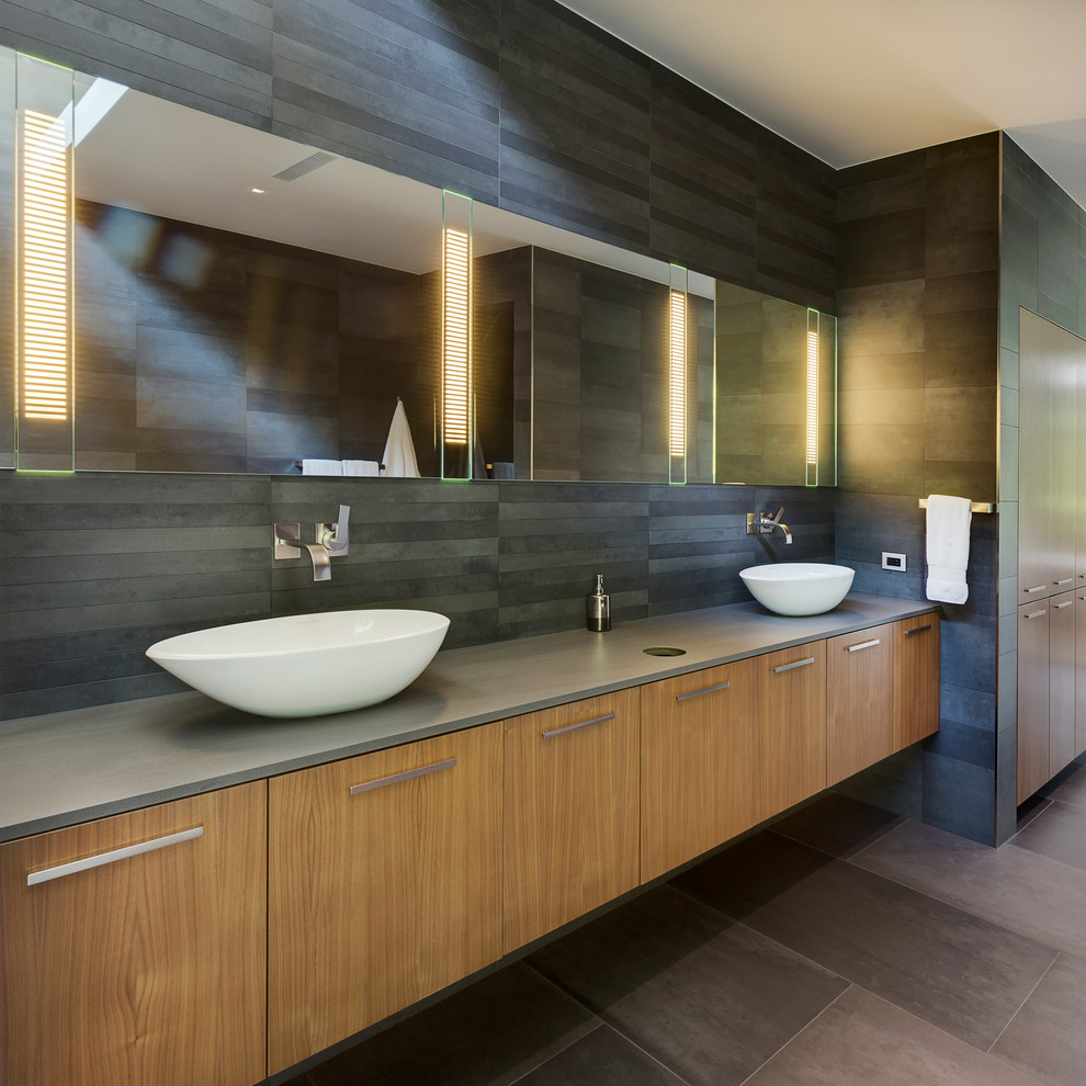 Cette photo montre une salle de bain tendance en bois clair pour enfant avec un placard à porte plane, un carrelage gris, un mur gris, un sol en carrelage de céramique, une grande vasque et un sol gris.