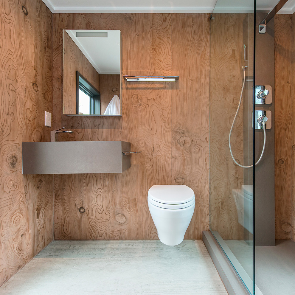 Inredning av ett modernt badrum för barn, med en öppen dusch, en vägghängd toalettstol, brun kakel, bruna väggar, betonggolv, ett väggmonterat handfat, grått golv och med dusch som är öppen