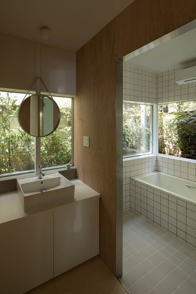 ストックホルムにあるコンテンポラリースタイルのおしゃれなマスターバスルーム (フラットパネル扉のキャビネット、白いキャビネット、アルコーブ型浴槽、白いタイル、ベージュの壁、ベッセル式洗面器) の写真