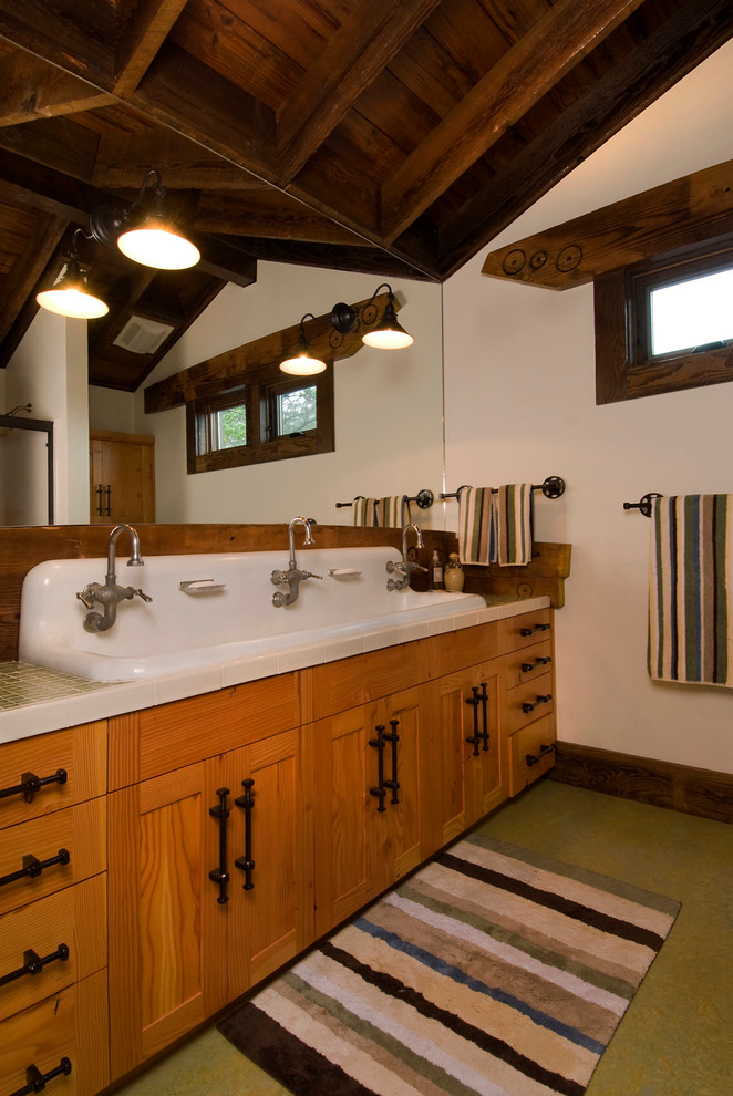 Rustik inredning av ett en-suite badrum, med ett avlångt handfat, luckor med infälld panel, skåp i mellenmörkt trä, kaklad bänkskiva, vita väggar, porslinskakel och skiffergolv