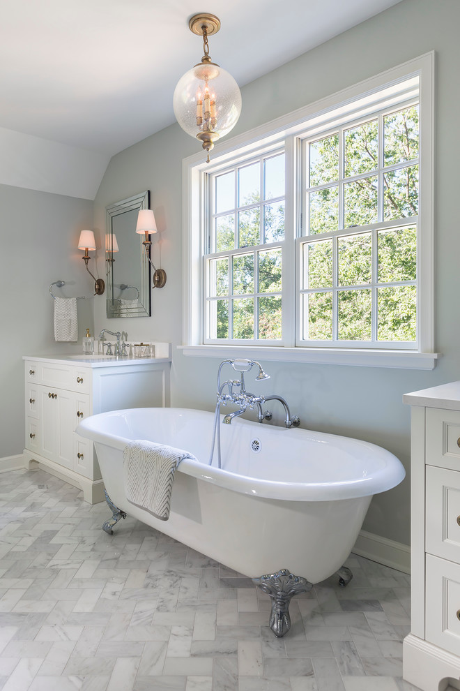Large classic ensuite bathroom in Minneapolis with recessed-panel cabinets, white cabinets, a claw-foot bath, marble flooring, engineered stone worktops, a shower/bath combination, white tiles, stone tiles, grey walls and a console sink.