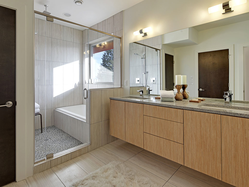 Modern inredning av ett en-suite badrum, med ett nedsänkt handfat, släta luckor, skåp i ljust trä, bänkskiva i återvunnet glas, ett platsbyggt badkar, en dubbeldusch, beige kakel och porslinskakel