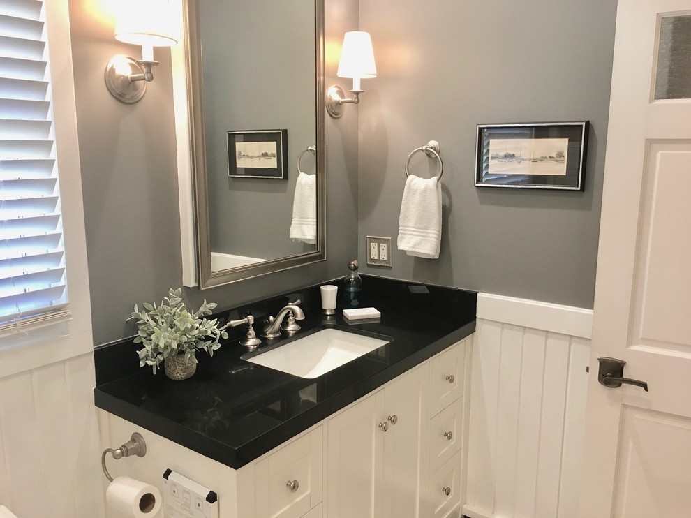 Diseño de cuarto de baño de estilo americano de tamaño medio con puertas de armario blancas, paredes grises, lavabo bajoencimera, ducha con puerta con bisagras, encimeras negras y ducha empotrada