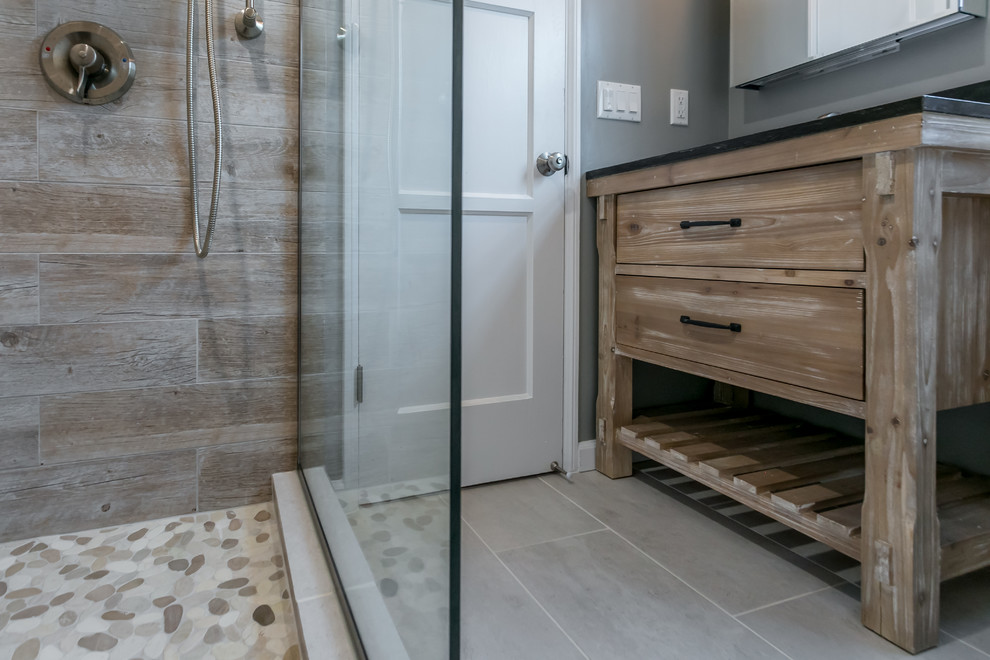 Mid-sized beach style 3/4 brown tile, gray tile and porcelain tile alcove shower photo in Los Angeles with furniture-like cabinets, medium tone wood cabinets, a two-piece toilet, gray walls, an undermount sink and quartzite countertops