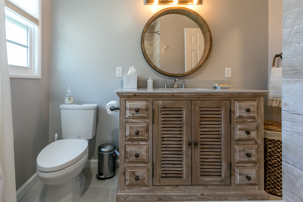 Exempel på ett mellanstort maritimt badrum med dusch, med möbel-liknande, skåp i mellenmörkt trä, ett badkar i en alkov, en dusch/badkar-kombination, en toalettstol med separat cisternkåpa, brun kakel, grå kakel, porslinskakel, grå väggar, ett undermonterad handfat och bänkskiva i kvartsit