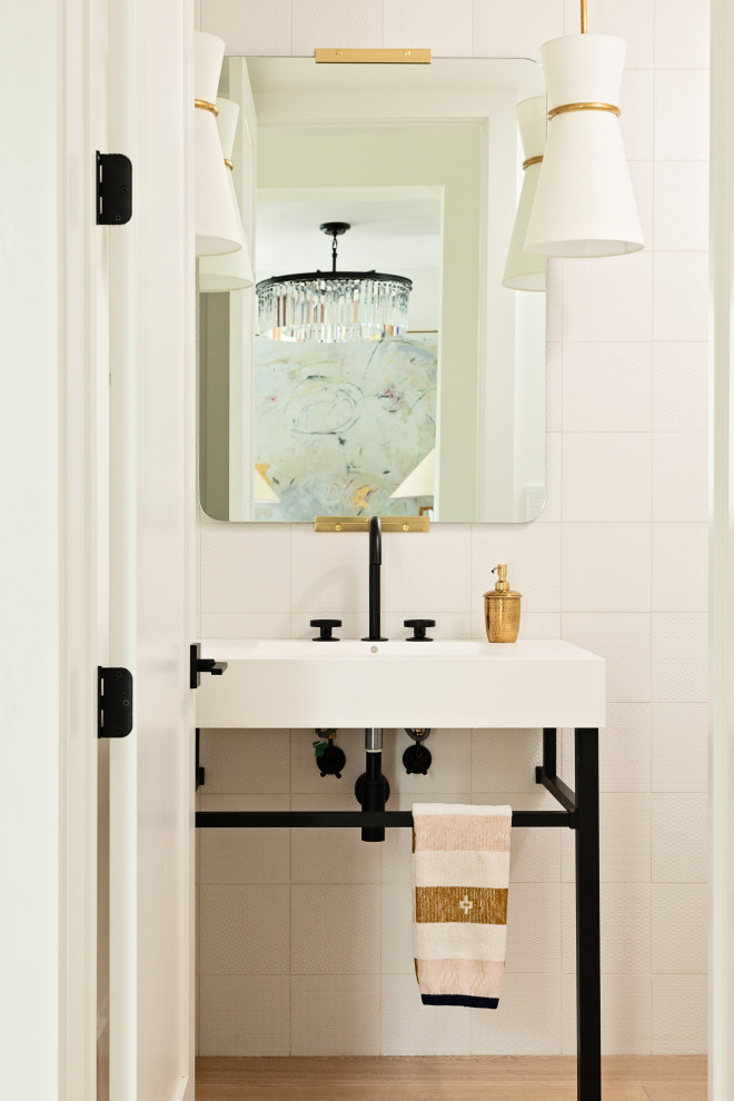 Klassisk inredning av ett litet badrum, med en toalettstol med hel cisternkåpa, vit kakel, keramikplattor, vita väggar, ljust trägolv och brunt golv