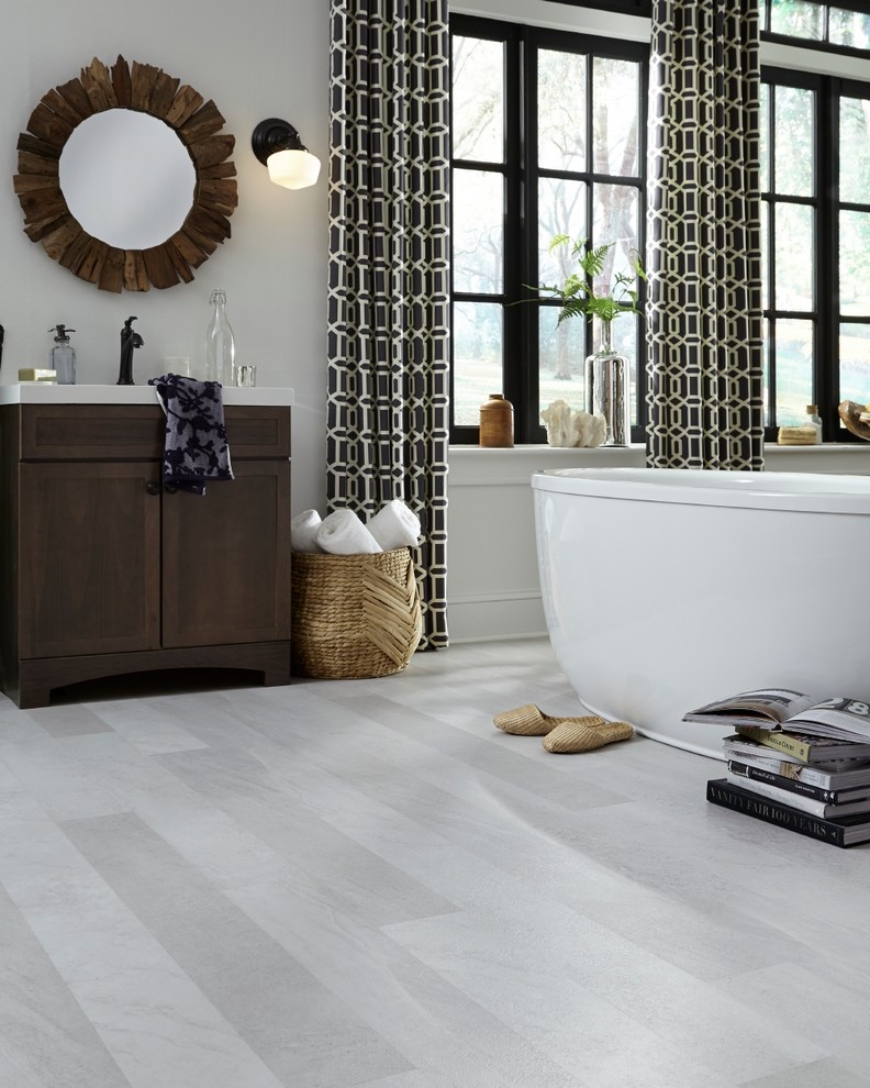 This is an example of a large contemporary ensuite bathroom in Philadelphia with freestanding cabinets, dark wood cabinets, a freestanding bath, vinyl flooring, a submerged sink, grey walls, solid surface worktops and grey floors.