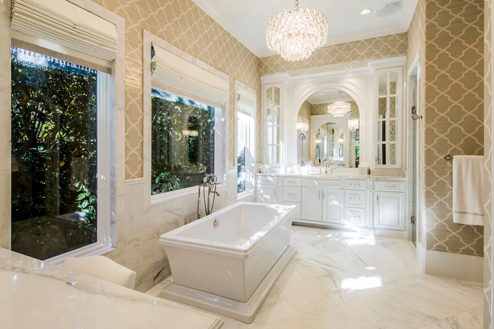 Exemple d'une grande salle de bain principale chic avec un placard avec porte à panneau surélevé, des portes de placard blanches, une baignoire indépendante, un carrelage blanc, du carrelage en marbre, un mur marron, un sol en marbre, un lavabo encastré, un plan de toilette en marbre et un sol blanc.