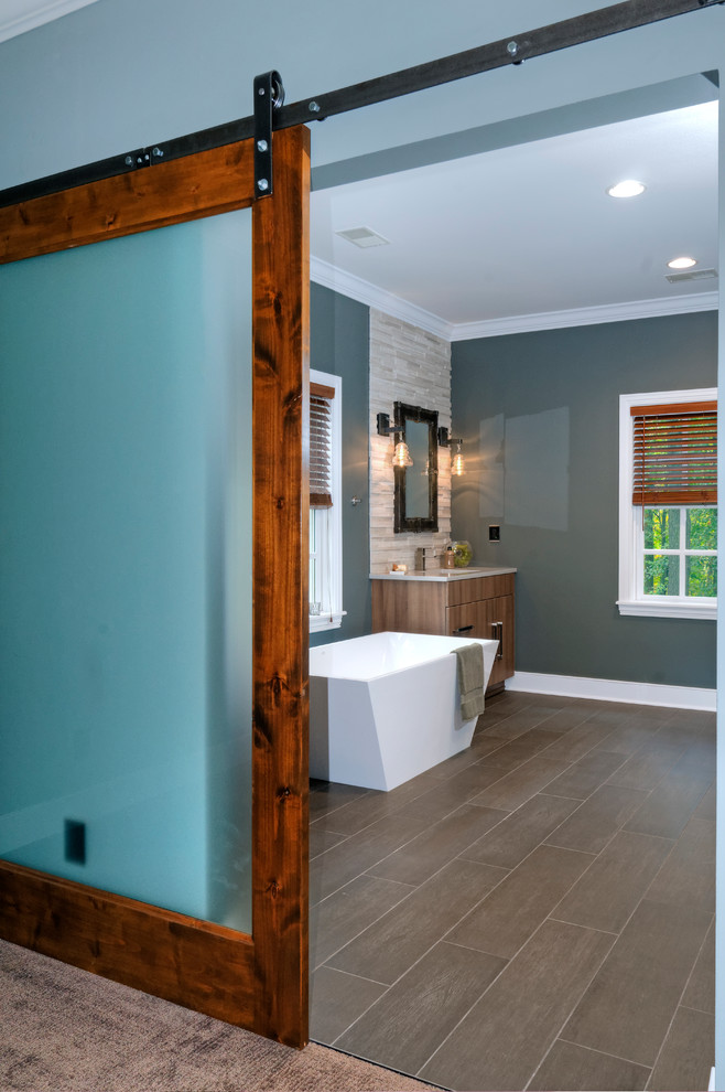 Modernes Badezimmer En Suite mit Unterbauwaschbecken, flächenbündigen Schrankfronten, hellen Holzschränken, freistehender Badewanne, braunen Fliesen und blauer Wandfarbe in Kolumbus