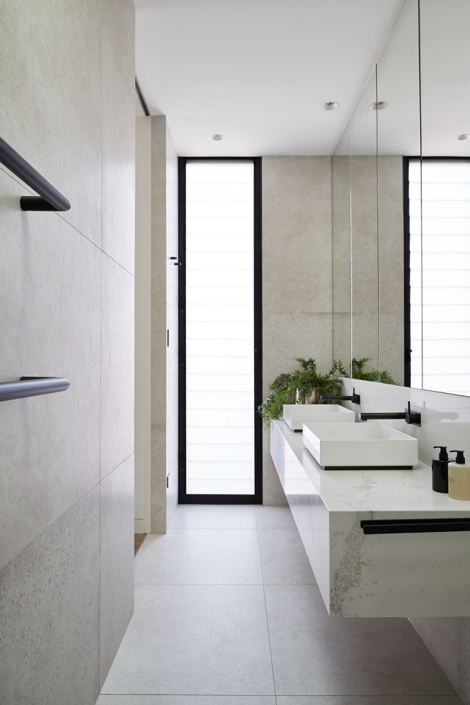Modern inredning av ett vit vitt badrum, med grå kakel, ett fristående handfat och grått golv