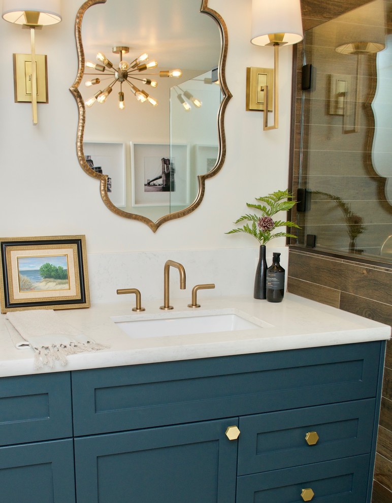 Inredning av ett litet vit vitt en-suite badrum, med blå skåp, ett badkar med tassar, brun kakel, bruna väggar, mellanmörkt trägolv, bänkskiva i kvartsit och dusch med gångjärnsdörr