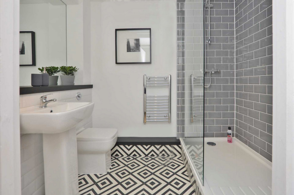 Photo of a small scandinavian shower room bathroom in London with freestanding cabinets, white cabinets, a walk-in shower, a one-piece toilet, white walls, vinyl flooring, a pedestal sink, black floors and an open shower.