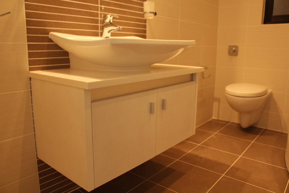 This is an example of a medium sized contemporary ensuite bathroom in Other with a console sink, flat-panel cabinets, white cabinets, laminate worktops, a corner bath, a shower/bath combination, a wall mounted toilet, beige tiles, ceramic tiles and ceramic flooring.