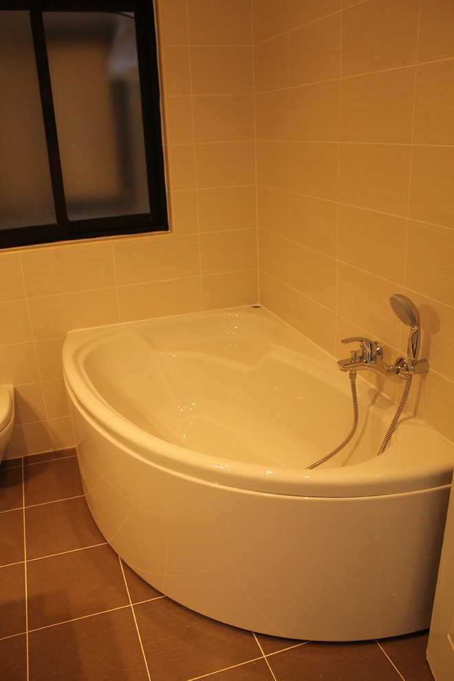 Foto på ett mellanstort funkis en-suite badrum, med ett konsol handfat, släta luckor, vita skåp, ett hörnbadkar, en dusch/badkar-kombination, en vägghängd toalettstol, beige kakel, keramikplattor och klinkergolv i keramik