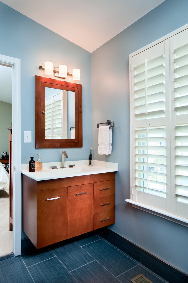 Modern inredning av ett litet en-suite badrum, med släta luckor, skåp i ljust trä, bänkskiva i akrylsten, blå kakel, porslinskakel, blå väggar och klinkergolv i porslin