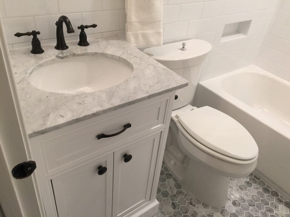 Cette photo montre une petite salle d'eau moderne avec un placard en trompe-l'oeil, des portes de placard blanches, une baignoire en alcôve, un combiné douche/baignoire, WC séparés, un carrelage blanc, un carrelage métro, un mur gris, un sol en marbre, un lavabo encastré, un plan de toilette en marbre, un sol gris, une cabine de douche avec un rideau et un plan de toilette gris.