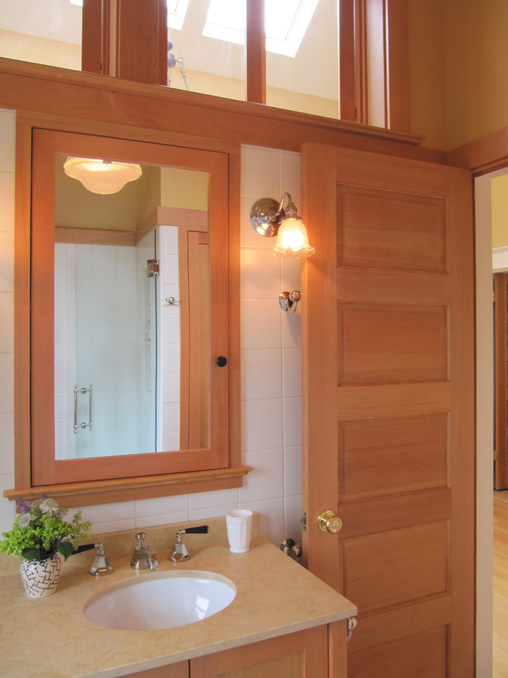 シアトルにある高級な小さなトラディショナルスタイルのおしゃれなバスルーム (浴槽なし) (アンダーカウンター洗面器、アルコーブ型シャワー、分離型トイレ、落し込みパネル扉のキャビネット、中間色木目調キャビネット、白いタイル、セラミックタイル、オレンジの壁、ライムストーンの床、ライムストーンの洗面台) の写真