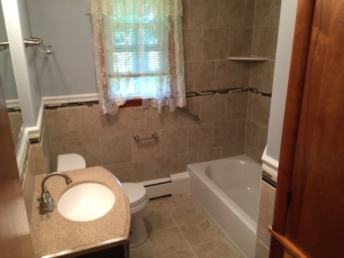 Exempel på ett mellanstort klassiskt badrum för barn, med ett integrerad handfat, möbel-liknande, skåp i mörkt trä, marmorbänkskiva, ett badkar i en alkov, en dusch/badkar-kombination, en toalettstol med separat cisternkåpa, beige kakel, porslinskakel, grå väggar och klinkergolv i porslin