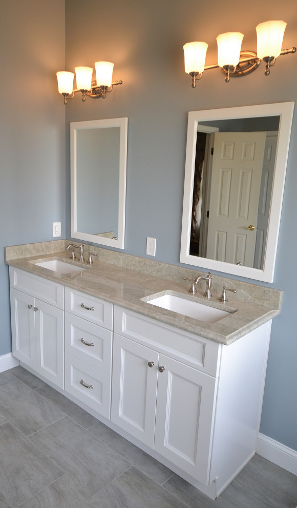 Bathroom - mid-sized transitional master beige tile and porcelain tile ceramic tile and gray floor bathroom idea in Philadelphia with recessed-panel cabinets, white cabinets, a one-piece toilet, blue walls, an undermount sink, quartzite countertops, a hinged shower door and beige countertops
