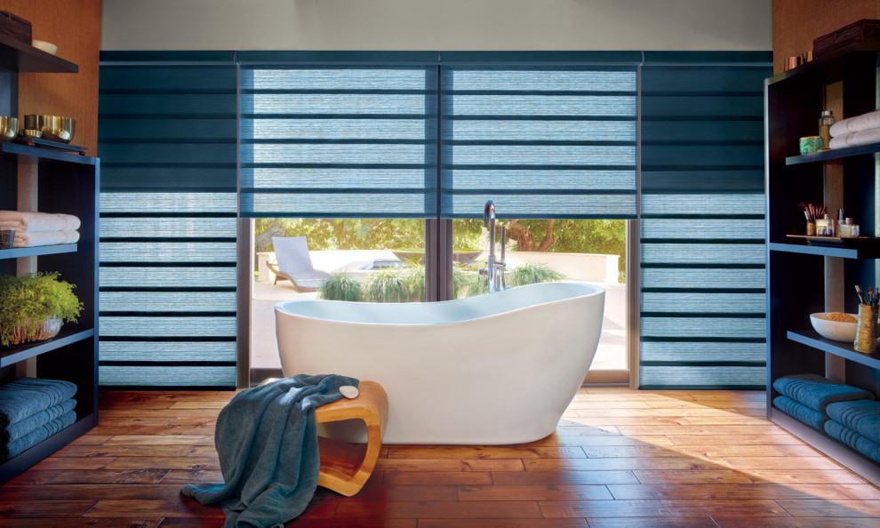 Esempio di una grande stanza da bagno padronale minimalista con vasca freestanding, pareti grigie, pavimento in legno massello medio e pavimento marrone