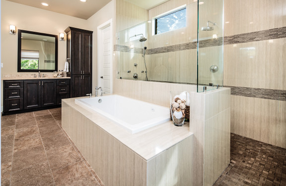 This is an example of a medium sized traditional ensuite bathroom in Austin with shaker cabinets, dark wood cabinets, a built-in bath, a built-in shower, a one-piece toilet, beige tiles, ceramic tiles, beige walls, limestone flooring, a submerged sink and limestone worktops.