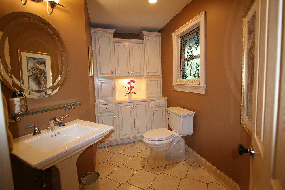 На фото: главная ванная комната среднего размера в классическом стиле с фасадами с выступающей филенкой, белыми фасадами, раздельным унитазом, коричневыми стенами, полом из керамической плитки, раковиной с пьедесталом и бежевым полом с