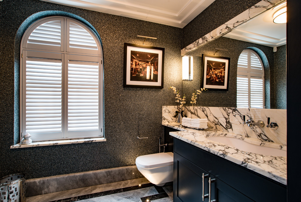 Idée de décoration pour une salle de bain design de taille moyenne avec WC suspendus, un mur gris, un lavabo encastré, un sol gris, un plan de toilette blanc, un sol en marbre, un plan de toilette en marbre, un placard à porte shaker et des portes de placard noires.