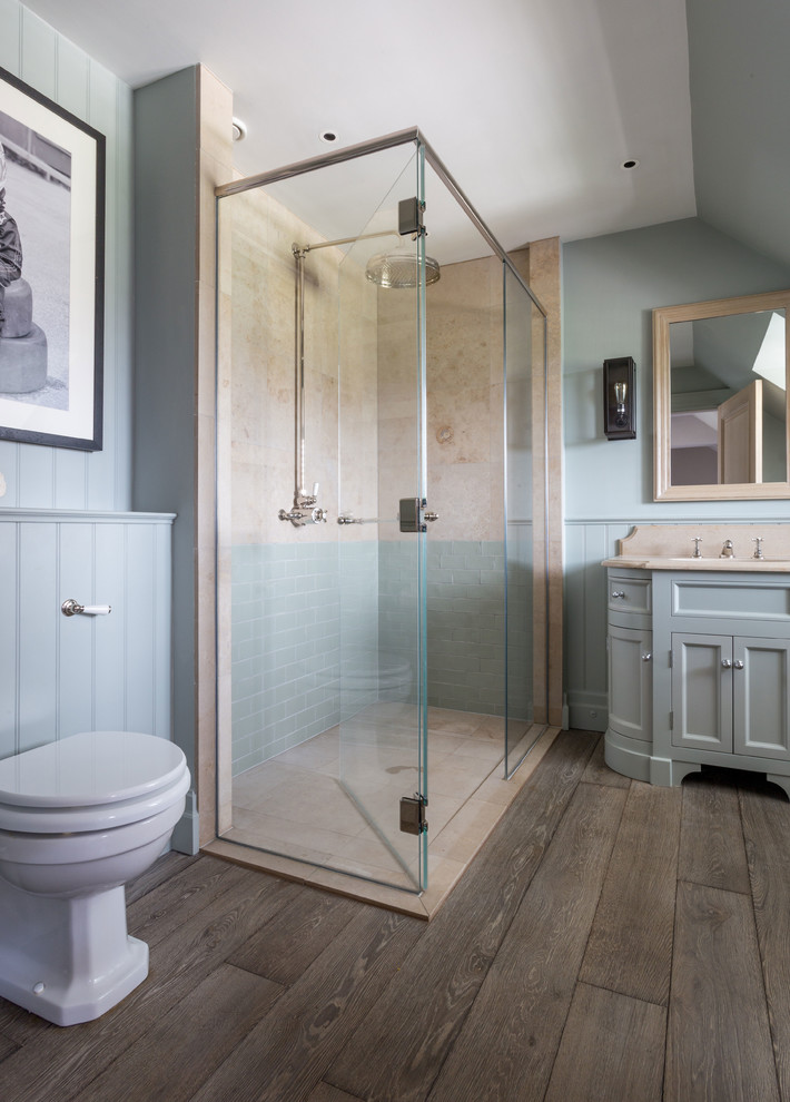 Design ideas for a medium sized farmhouse ensuite bathroom in West Midlands with recessed-panel cabinets, grey cabinets, a walk-in shower, a one-piece toilet, blue walls, medium hardwood flooring, a built-in sink, marble worktops, brown floors and a hinged door.