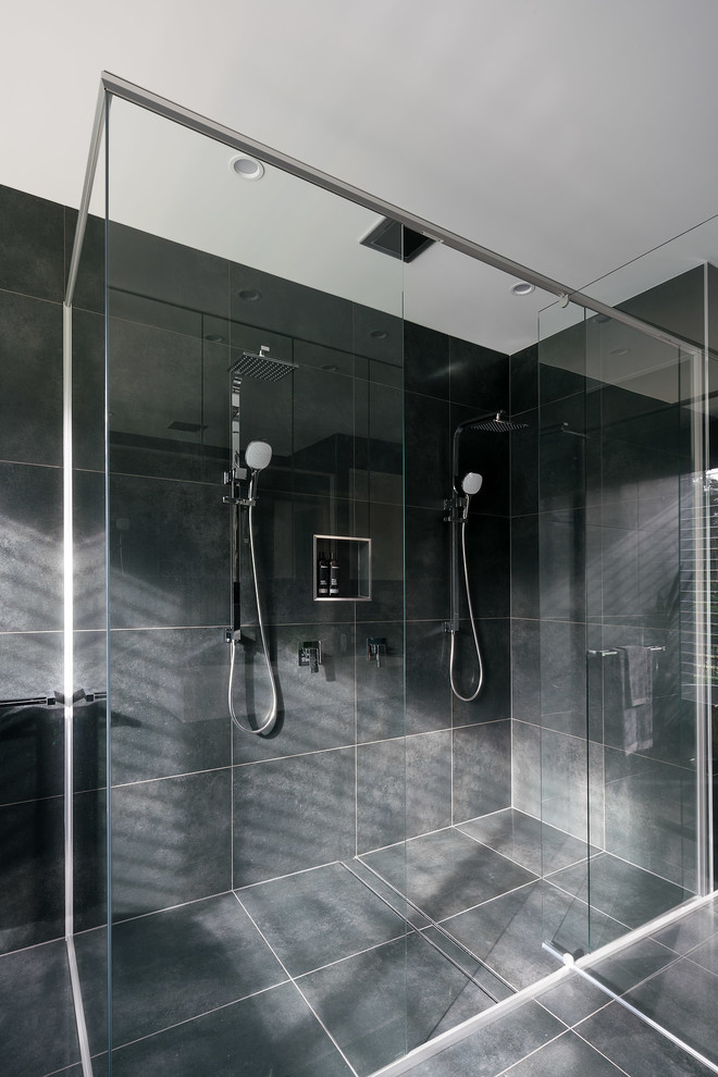 Example of a large trendy master black tile and porcelain tile porcelain tile and black floor bathroom design in Sunshine Coast with a one-piece toilet, black walls, a wall-mount sink, solid surface countertops, a hinged shower door and white countertops