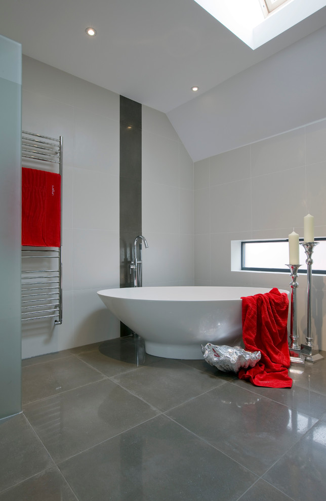 На фото: ванная комната в современном стиле с отдельно стоящей ванной и серой плиткой с