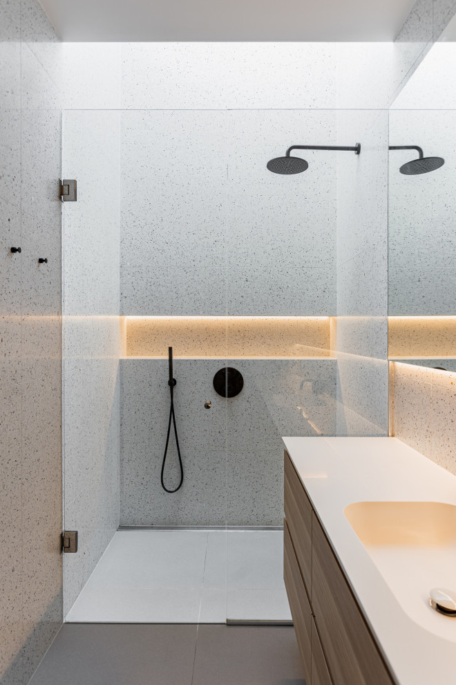 Inspiration for a modern bathroom in London with flat-panel cabinets, medium wood cabinets, a built-in shower, grey tiles, an integrated sink, grey floors, a hinged door, white worktops, a single sink and a floating vanity unit.