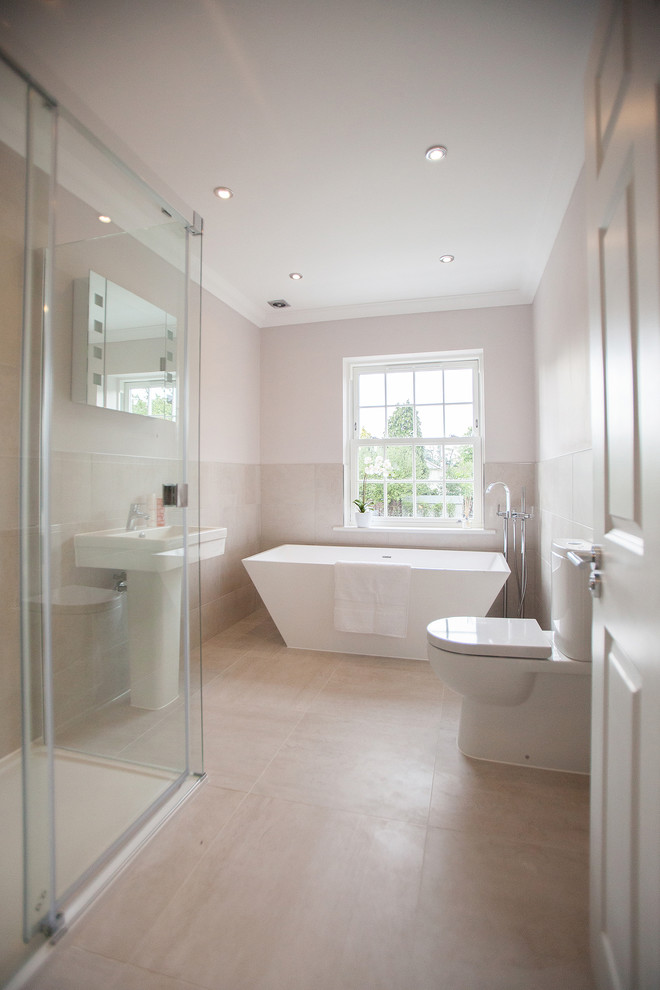 Modelo de cuarto de baño rectangular contemporáneo con lavabo con pedestal, bañera exenta, sanitario de dos piezas, baldosas y/o azulejos beige y ducha esquinera
