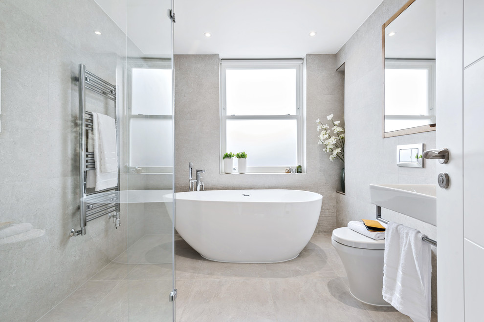 Diseño de cuarto de baño actual con bañera exenta, sanitario de pared, baldosas y/o azulejos blancos, paredes blancas, lavabo suspendido y suelo blanco