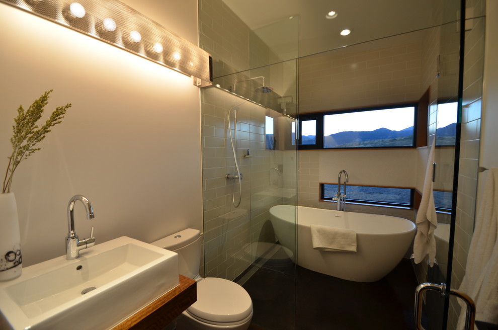 This is an example of a medium sized contemporary ensuite bathroom in Seattle with open cabinets, a freestanding bath, a walk-in shower, a one-piece toilet, white tiles, porcelain tiles, white walls, concrete flooring, a trough sink, wooden worktops, brown floors and a hinged door.