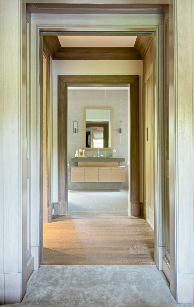 На фото: главная ванная комната среднего размера в стиле неоклассика (современная классика) с плоскими фасадами, светлыми деревянными фасадами, серой плиткой, отдельно стоящей ванной, серыми стенами, бетонным полом и врезной раковиной с