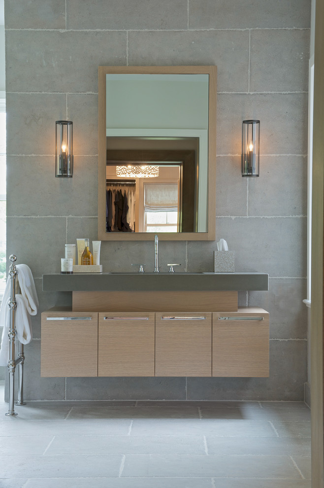 Inspiration for a mid-sized transitional gray tile concrete floor bathroom remodel in New York with flat-panel cabinets, light wood cabinets, gray walls, an undermount sink and solid surface countertops