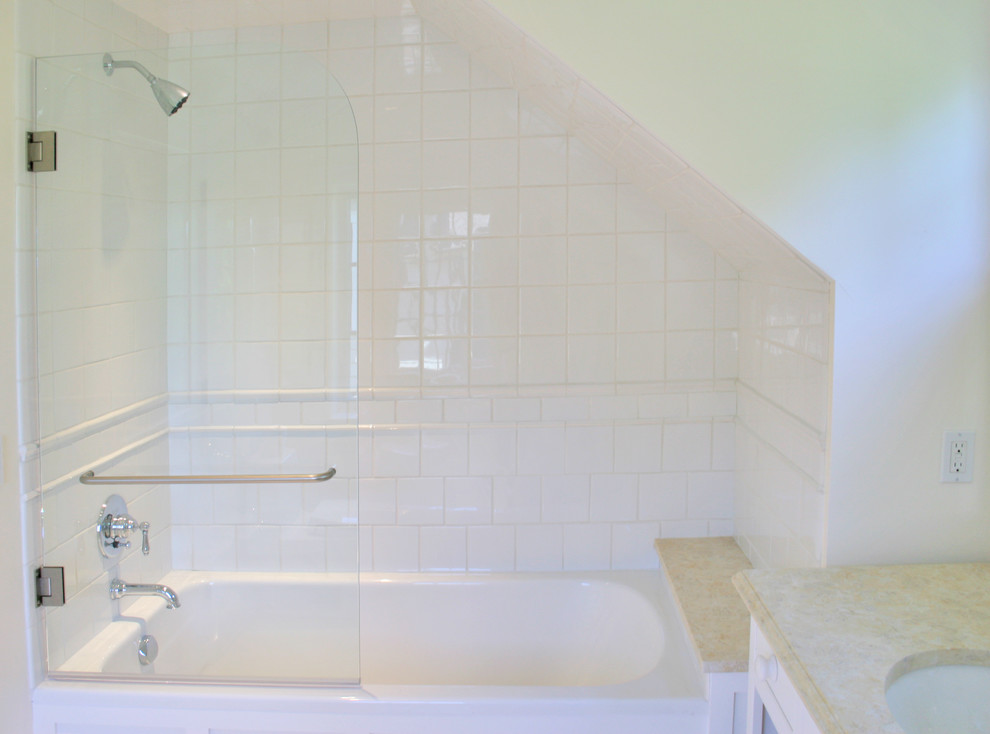 Foto på ett mellanstort vintage en-suite badrum, med luckor med infälld panel, vita skåp, ett badkar i en alkov, en dusch/badkar-kombination, vita väggar, en toalettstol med hel cisternkåpa och ett undermonterad handfat