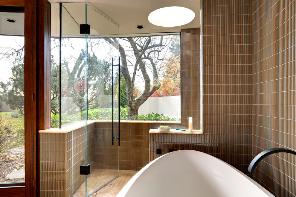 Bild på ett stort funkis en-suite badrum, med en kantlös dusch, ett fristående badkar, skåp i mellenmörkt trä, en toalettstol med hel cisternkåpa, grå kakel, keramikplattor, bruna väggar och marmorgolv