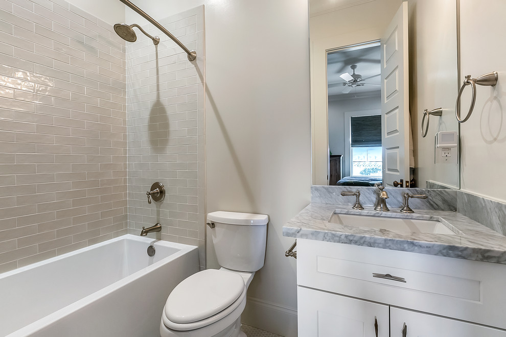 Пример оригинального дизайна: маленькая ванная комната в современном стиле с фасадами в стиле шейкер, желтыми фасадами, ванной в нише, душем над ванной, раздельным унитазом, серой плиткой, керамической плиткой, серыми стенами, душевой кабиной, врезной раковиной, мраморной столешницей, шторкой для ванной и серой столешницей для на участке и в саду