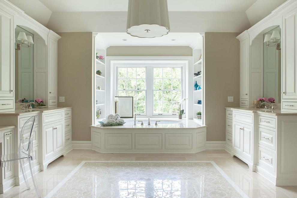На фото: ванная комната в классическом стиле с врезной раковиной, фасадами с выступающей филенкой, белыми фасадами, полновстраиваемой ванной, бежевой плиткой, бежевыми стенами и окном