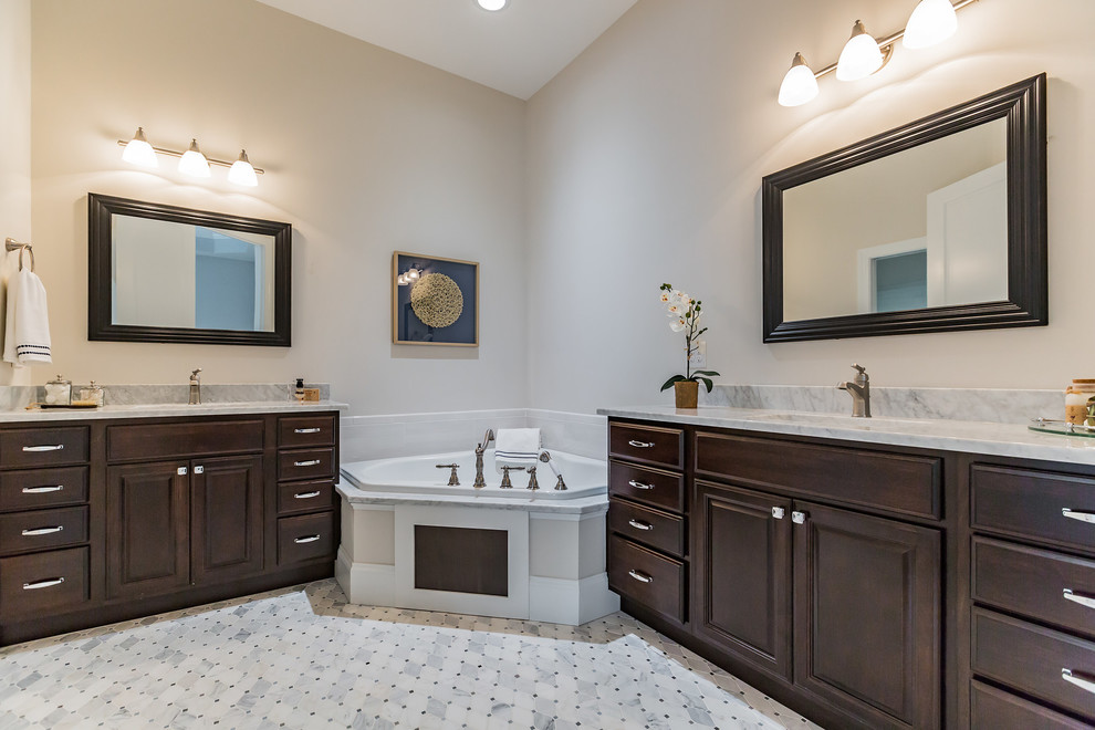 Inspiration for a large classic ensuite bathroom in Philadelphia with recessed-panel cabinets, dark wood cabinets, a corner bath, an alcove shower, white tiles, marble tiles, beige walls, marble flooring, a submerged sink, marble worktops, grey floors and a hinged door.